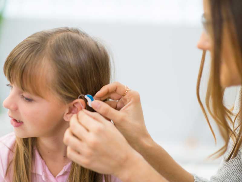 A young girl being fitted with hearing aids.