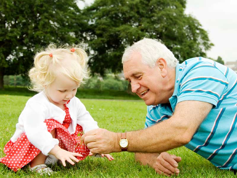 Older man playing with his grand daughter.